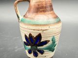 a brown and blue vase with a flower on it