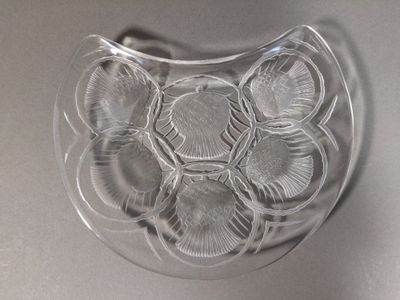 un saladier en verre transparent rempli de coquillages, posé sur une table