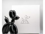Le chien en ballon noir se trouve à côté d'une boîte blanche sur laquelle est dessiné un chien