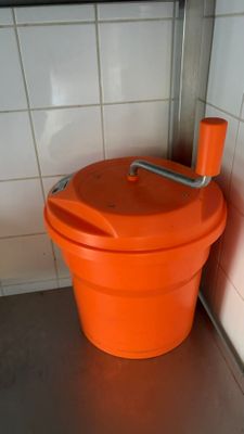 an orange bucket with a handle sitting on the floor