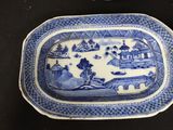 a blue and white plate with a picture of a village on it