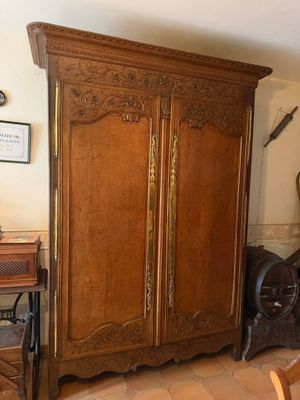 une grande armoire en bois dans une pièce où se trouvent une table et une chaise