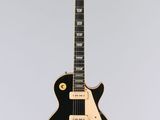 une guitare électrique suspendue à une ficelle sur un mur blanc