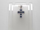 un gros plan sur un pendentif en forme de croix, orné de diamants bleus et blancs