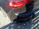 the rear end of a black car parked in a parking lot