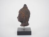 a close up of a statue of a buddha head on a stand