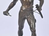 statue en bronze représentant un homme tenant une épée et un bouclier
