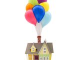 une petite maison sur le toit de laquelle est accroché un bouquet de ballons