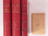 trois livres rouges posés sur une table blanche, à côté d'un livre