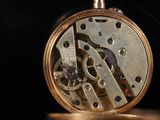 a close up of a pocket watch on a black background