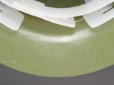 a green vase with a white lid on a table