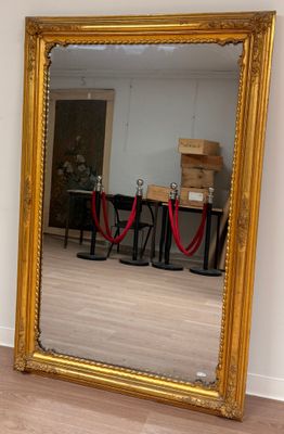 a large mirror in the middle of a room with a red rope