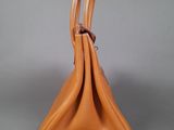 an orange leather handbag sitting on a gray surface