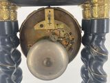 a black and gold clock on a stand with a white background