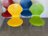 Quatre chaises colorées sont alignées contre un mur dans une pièce