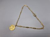 a gold chain bracelet with a coin on it