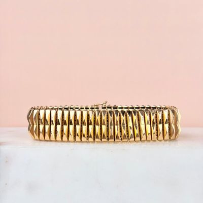 a close up of a gold bracelet on a marble surface