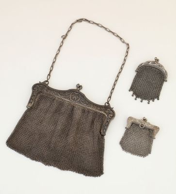an antique silver mesh purse with a chain strap and two small silver purses