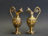 une paire de vases anciens en laiton posés sur un socle, sur fond gris