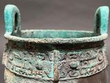 a close up of a bronze pot with a handle on a stand