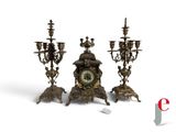 three candles and a clock sitting on a table