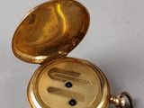an antique gold pocket watch with a key on a white surface