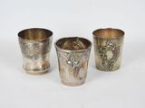 trois tasses en argent posées l'une à côté de l'autre sur une surface blanche