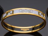 two gold and white bang bracelets with the word hermess on them