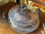 a silver plate with a bird on it on a wooden table