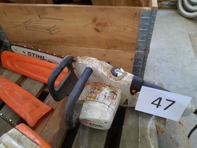 une tronçonneuse posée sur une palette à côté d'autres outils