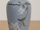 un vase bleu orné de fleurs blanches, posé sur une table
