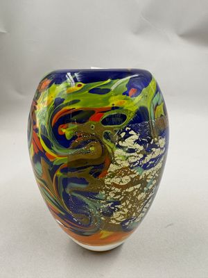 un vase coloré posé sur une table, sur fond blanc