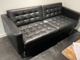un canapé en cuir noir placé dans un coin d'une pièce