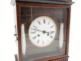une petite horloge en bois avec des chiffres romains sur le cadran