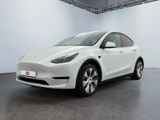 the white tesla model y is parked in a white room