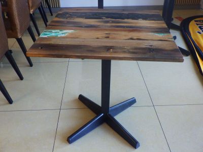 une table en bois avec quatre pieds noirs posée sur un sol carrelé