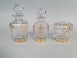 trois flacons de parfum en verre ornés de finitions dorées, posés sur un fond blanc