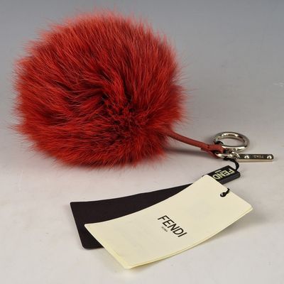 une boule de fourrure rouge accrochée à un porte-clés, avec une étiquette