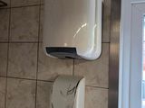 une photo d'une salle de bains avec des toilettes et un distributeur de savon fixé au mur