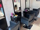 une photo d'un salon de coiffure avec des fauteuils et des miroirs