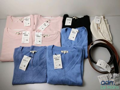Plusieurs chemises et une ceinture sont posées sur une table