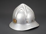 an old silver fire helmet with a gold emblem on it