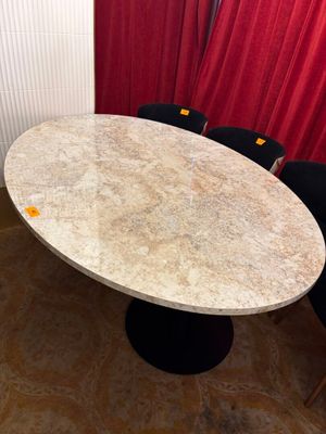 une table et des chaises en marbre dans une pièce aux rideaux rouges