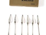 six forks and a box of empty forks sitting on a white surface
