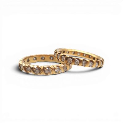 two gold rings with diamonds on them on a white background