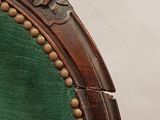 an old chair with a green upholstered seat and wood trim