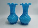 une paire de vases en verre bleu posés sur une table blanche