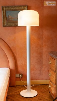 une lampe posée par terre à côté d'un lit