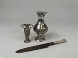 two silver vases and a knife sitting next to each other