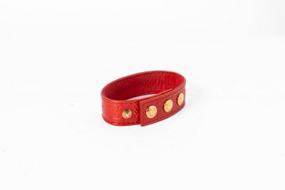 un gros plan d'un bracelet en cuir rouge posé sur une surface blanche